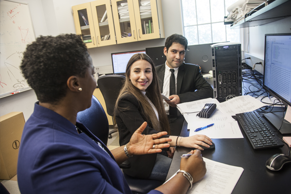 Three professionals in a discussion around a desk with computers, representing potential career paths in engineering