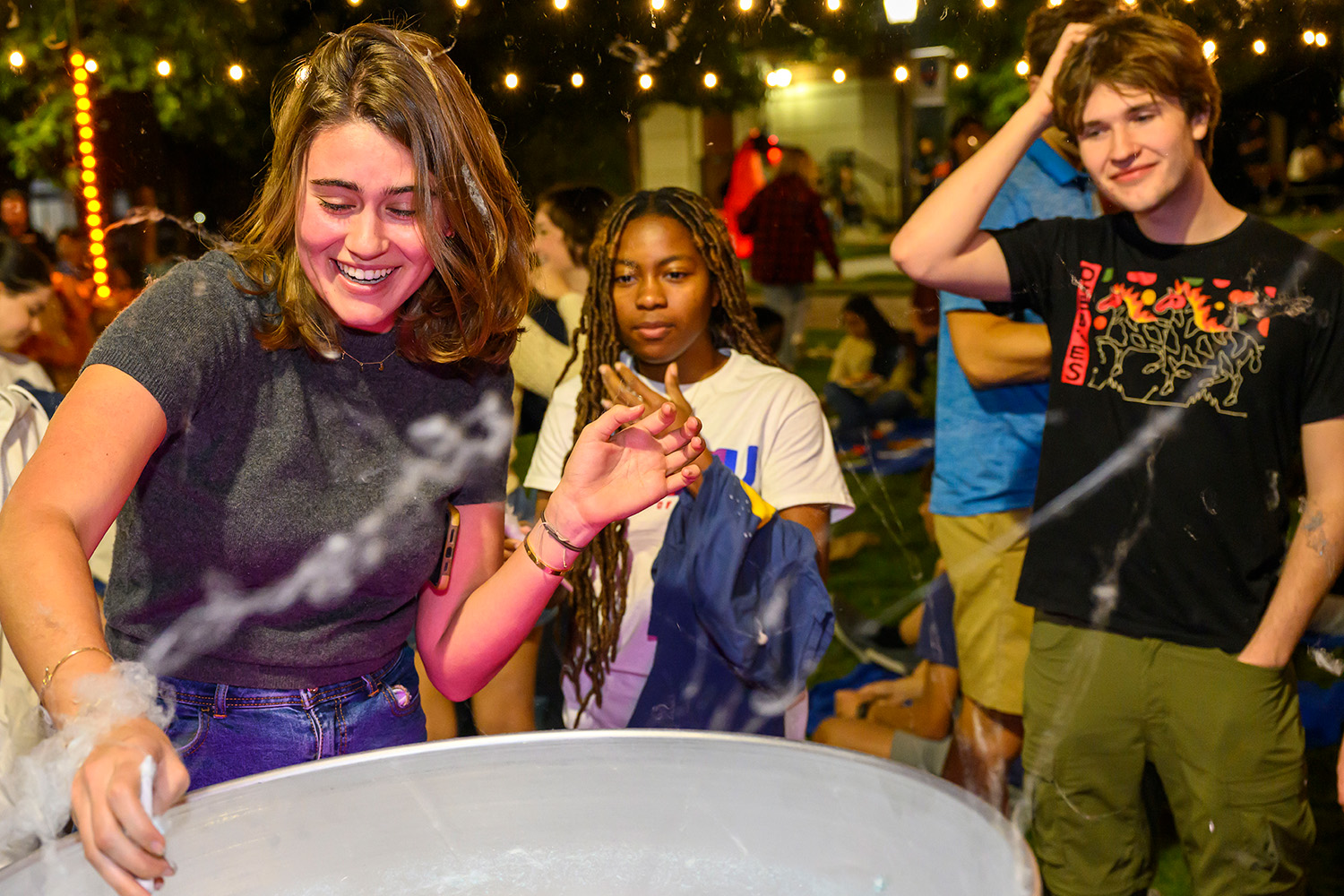 Students gathered around a large cooking pot. 