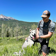 Zach Turner hiking with a dog and a mountain in the background