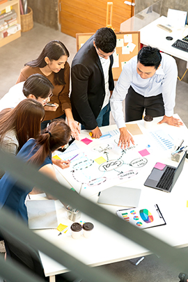 An executive leading a group of business people on a project around a circular table.