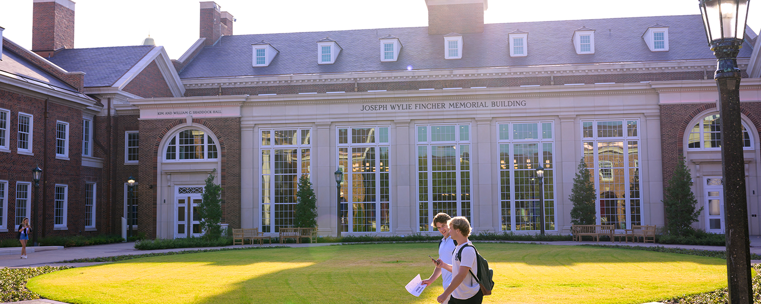 Two students crossing the quad in front of the Fincher building at the Cox School of Business