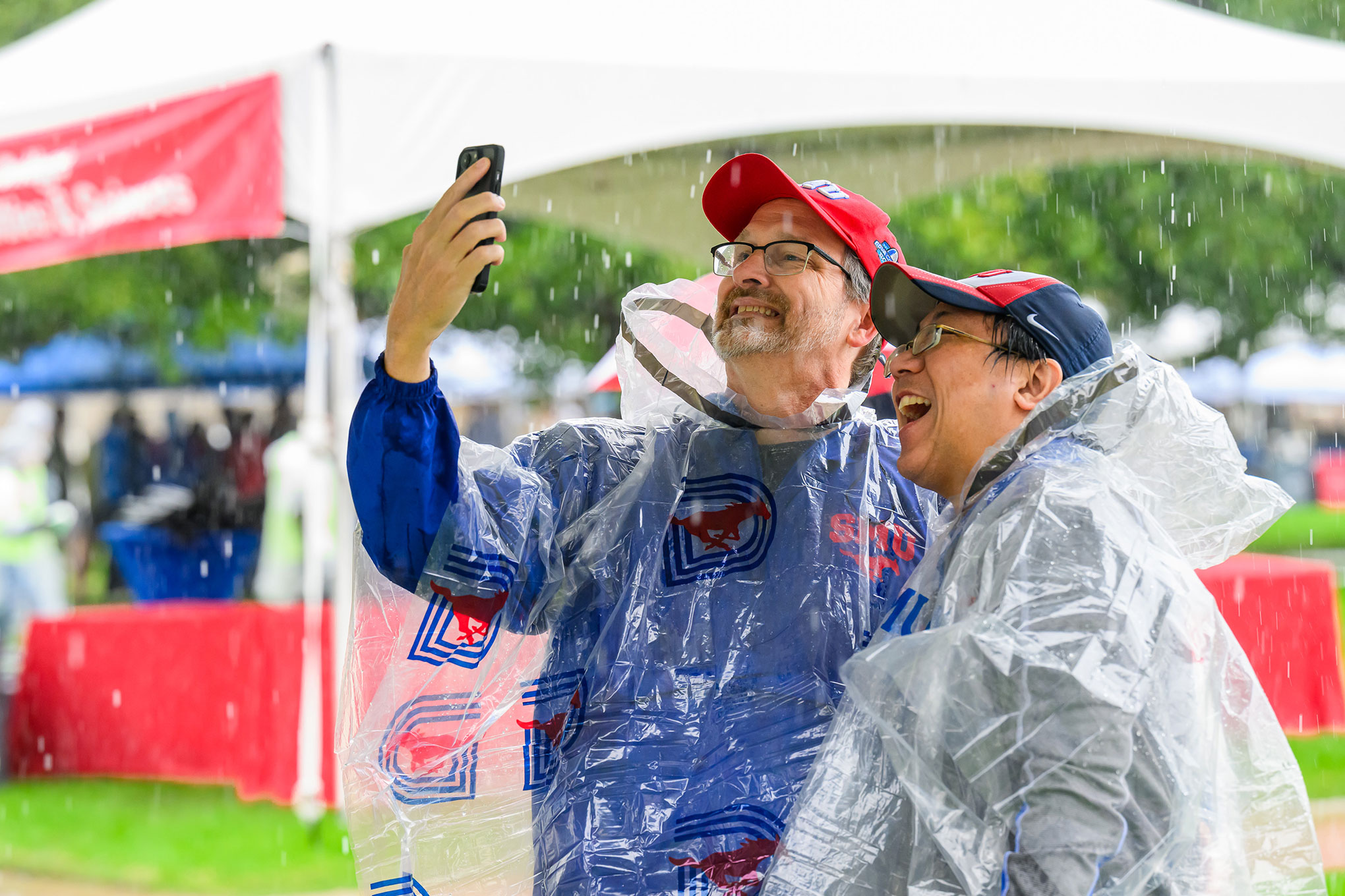 色花堂_色花堂 98堂 alumni wearing ponchos take a selfie during a rain shower