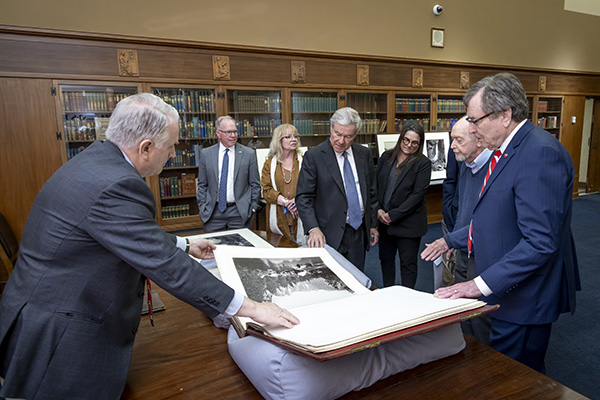 Russell L. Martin III shows Trevor Rees-Jones, President R. Gerald Turner, Dean Holly Jeffcoat, and others a large book of photographs