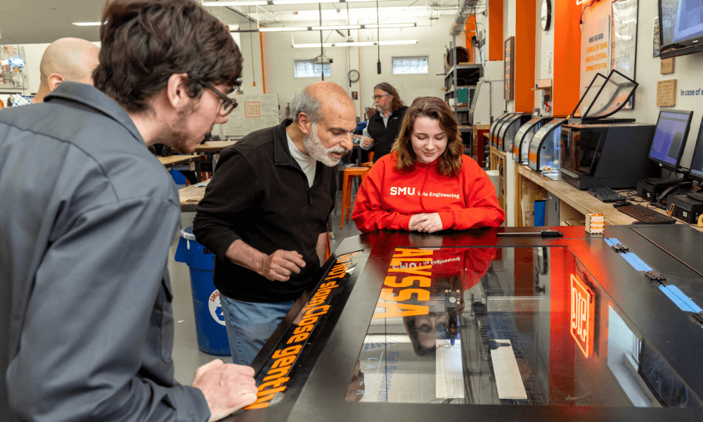 teacher and students work around a machine