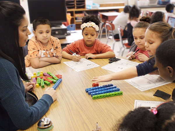Teacher working with middle school students using fraction manipulatives.