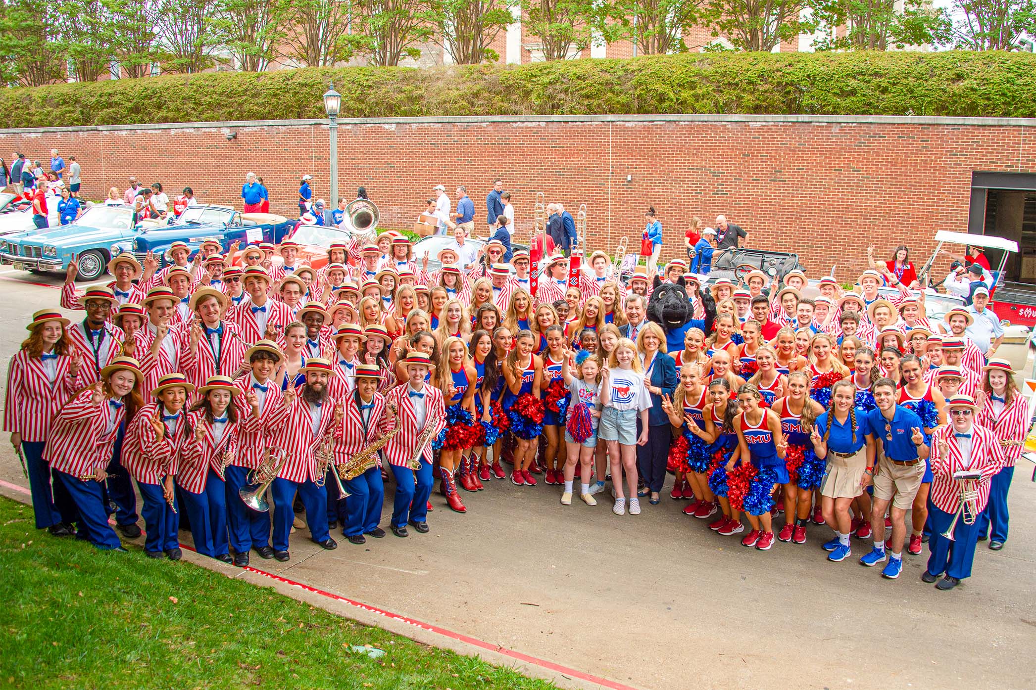 色花堂_色花堂 98堂 Mustang Band with cheerleaders, Peruna mascot, University President, and friends standing outside in front of brick wall