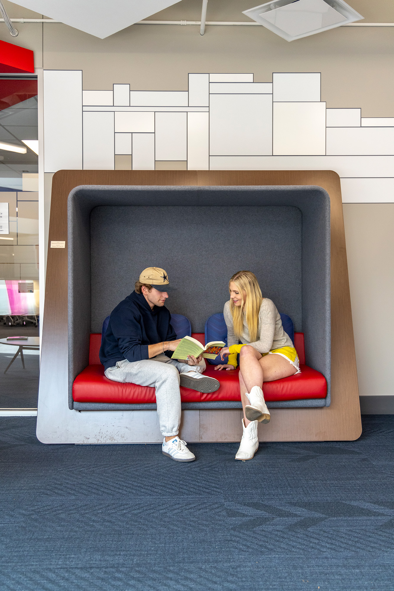 two people sitting in booth reading a book