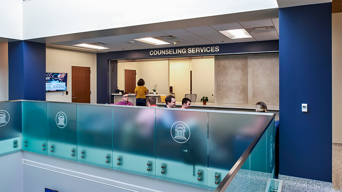 people sitting in chairs and standing in front of desk for counseling services