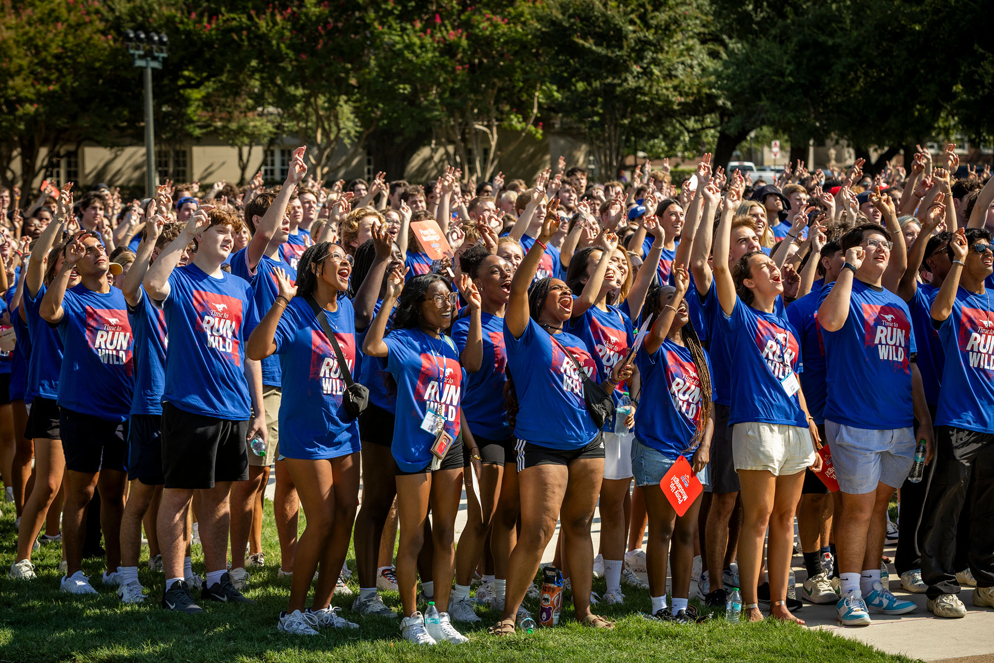 students standing outside looking up at camera for photo and holding two fingers in the air for the 色花堂_色花堂 98堂 pony up hand sign