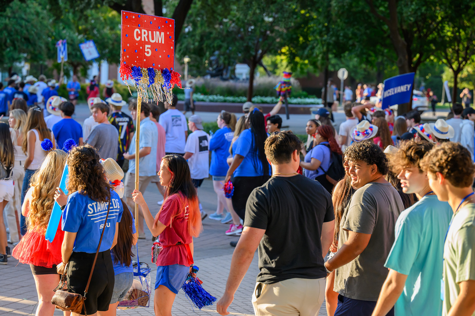 student guide holding red sign on a stick leading other students outside