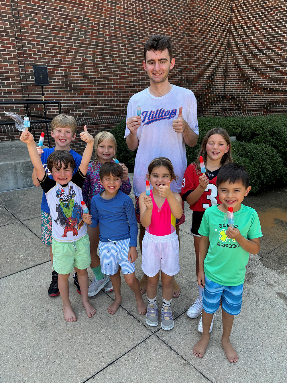 seven children and one adult smiling with popsicles