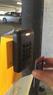 person holding ID card to card reader in parking garage